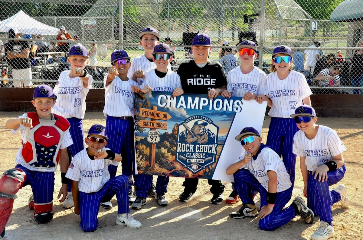 The Ravens baseball team pointing their championship rings at the camera around a Rock Chuck Classic champions banner