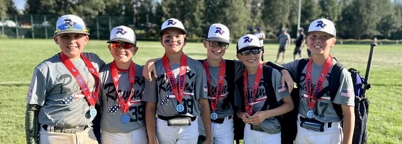 Six Ravens players in caps and gray jerseys, arms around each other, wearing red finalist medals after a tournament