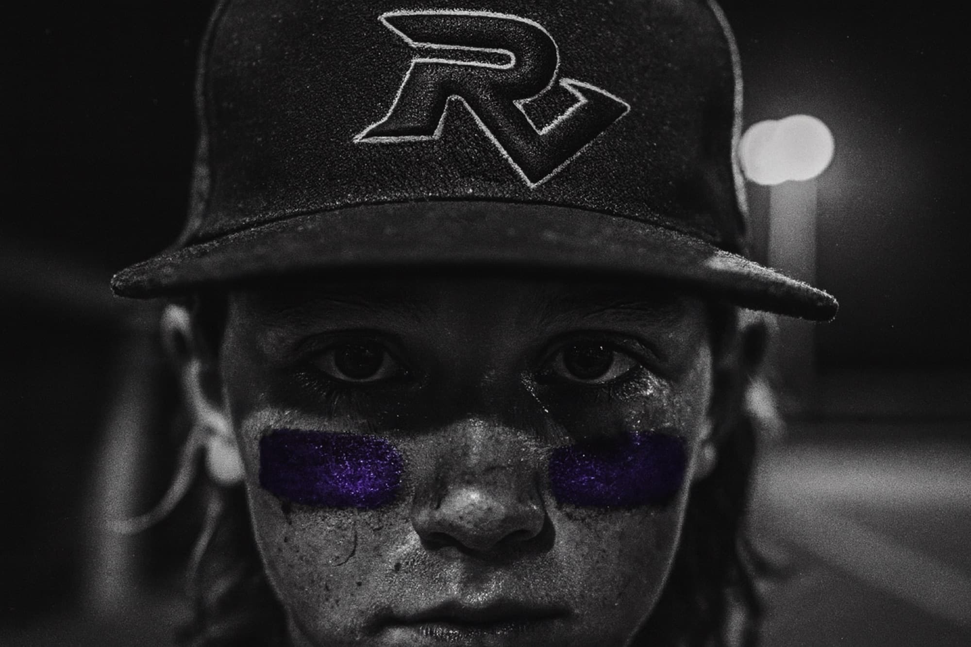 A Ravens player's eyes under his cap brim, purple eye black smeared beneath them
